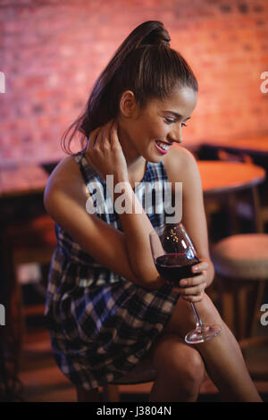 Giovane donna avente il vino rosso in pub Foto Stock