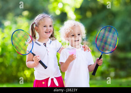 Attiva la ragazza in età prescolare e ragazzo giocando badminton in tribunale aperto in estate. I bambini a giocare a tennis. Scuola di sport per i bambini. Racchette e volano spor Foto Stock