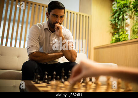 Imprenditore pensosa giocando a scacchi con il collega di sesso femminile in office Foto Stock