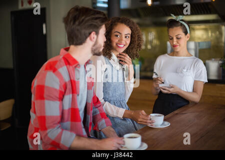 Donna sorridente guardando amico ponendo fine alla cameriera del ristorante Foto Stock