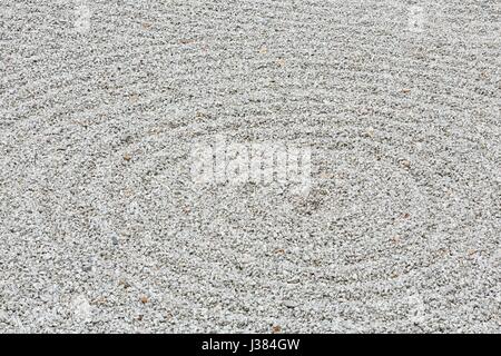 Circolare ghiaia rastrellata pattern in un giardino zen Foto Stock