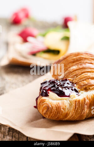 Cornetto con la marmellata sulla tavola di legno, tavolo da pranzo Foto Stock