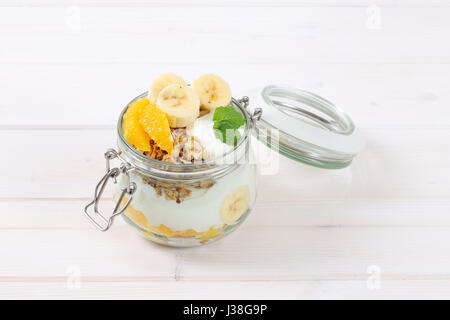 Vasetto di muesli con yogurt e frutta fresca su sfondo bianco Foto Stock