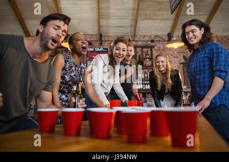 Giovani amici a giocare la birra pong gioco sul tavolo in bar Foto Stock