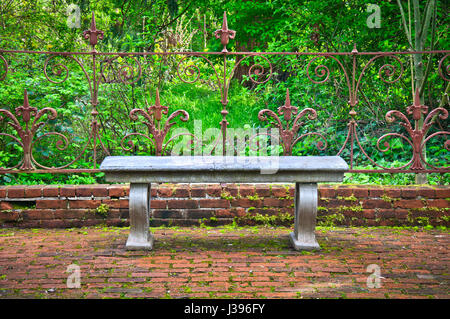 Il vecchio banco in inglese formale giardino ornato di ferro battuto recinzione Foto Stock