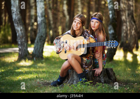 Due ragazze hippie con chitarra in una Foresta estate Foto Stock