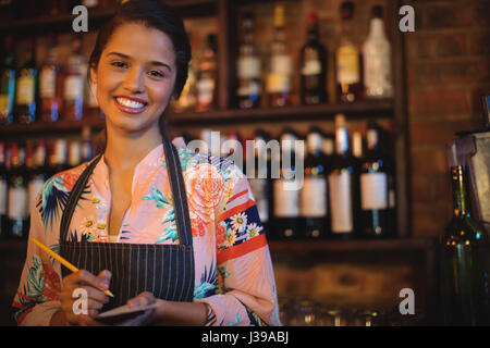 Ritratto di cameriera prendendo un ordine su notepad in pub Foto Stock