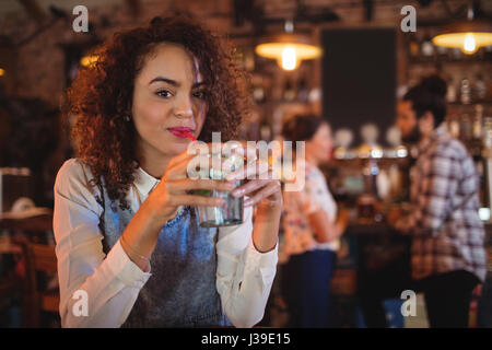 Ritratto di giovane donna con un cocktail di benvenuto in pub Foto Stock