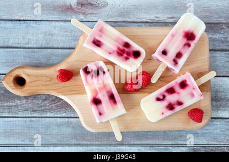 In casa lampone vaniglia popsicles su una scheda a pale con legno rustico sfondo Foto Stock