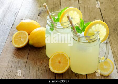 Due mason jar bicchieri di limonata fatta in casa su un rustico sfondo di legno Foto Stock