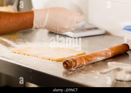 Uomo da forno preparare deliziosi biscotti di Natale in un negozio da forno e cospargere di farina sull'impasto Foto Stock