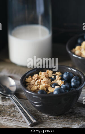 Muesli con mirtilli freschi in nero bocce su una tavola in legno rustico Foto Stock