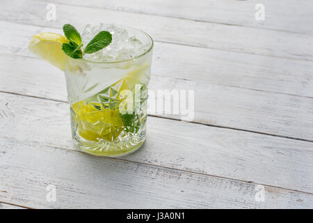 Cocktail con calce , ghiaccio e menta piperita in bianco sullo sfondo di legno. Foto Stock