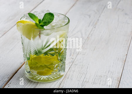 Bevanda estiva mojito con lime e foglie di menta bianca su sfondo di legno con copia spazio. Foto Stock