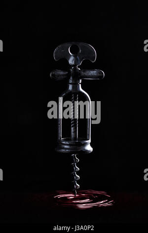 Cavatappi antichi appesi in aria su uno sfondo nero. Un antico cavatappi levita e lascia i cerchi sulla superficie del vino. Struttura di cavatappi su Foto Stock