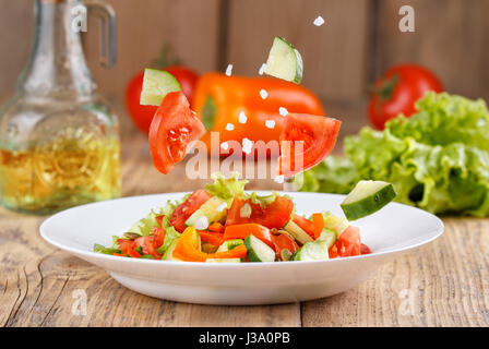 Estate light air insalata di verdure fresche su uno sfondo di legno. La levitazione ingredienti insalata. Ancora in vita in uno stile rustico. Insalata di verdure da th Foto Stock