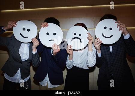 Ufficio lavoratori cercando su sorridente e triste maschere Foto Stock