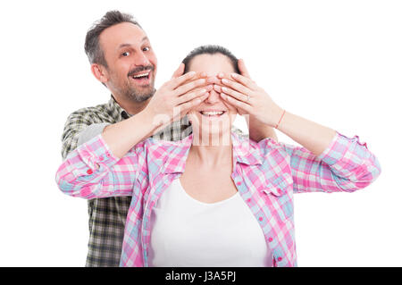 Allegro uomo che copre la sua gli occhi di donna facendo una sorpresa su bianco di sfondo per studio Foto Stock