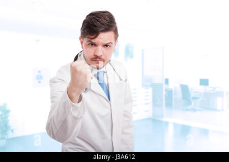 Medico maschio agenti aggressivi e mostrando il pugno e minacciando di qualcuno con copyspace Foto Stock