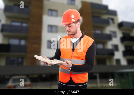 Costruttore maschio per esterno al luogo di lavoro tenendo la sua guanti di protezione Foto Stock