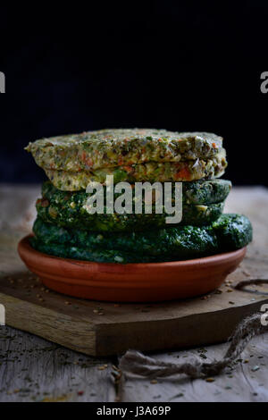 Primo piano di alcune differenti materie veggie hamburger in un piatto di terracotta, su una tavola in legno rustico Foto Stock