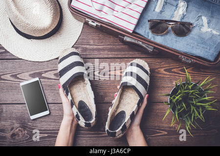 Preparazioni per il viaggio concetto sul tavolo di legno con aprire la valigia, capi di abbigliamento e accessori Foto Stock