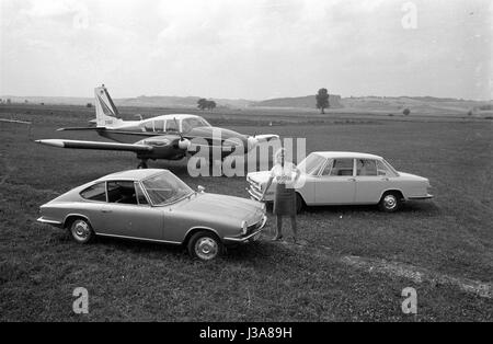 Una donna in posa con due vetture nella parte anteriore di un aeromobile leggero, 1963 Foto Stock