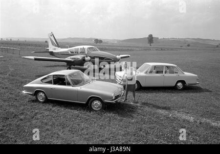 Una donna in posa con due vetture nella parte anteriore di un aeromobile leggero, 1963 Foto Stock