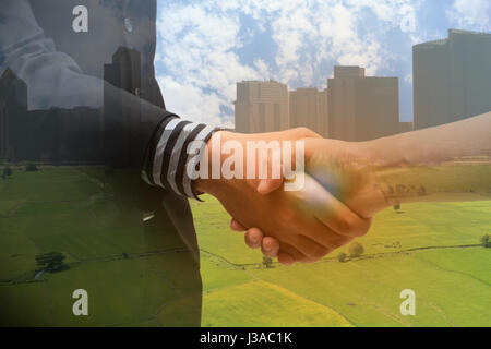 Doppia esposizione di handshake con blur city e il concetto di agricoltura con il fake flare,la partnership tra uomo di affari e agricoltore Foto Stock