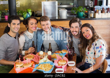 Ritratto di felice amici seduto da cibi e bevande serviti al tavolo nel ristorante Foto Stock