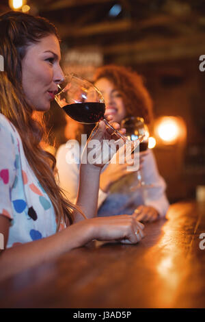 Due belle giovani donne avente il vino rosso in pub Foto Stock