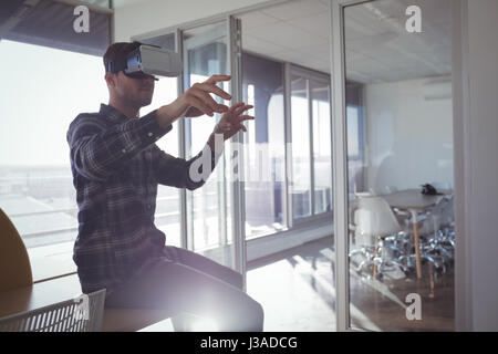 Imprenditore creativo gesticolando mentre vivendo la realtà virtuale in ufficio Foto Stock