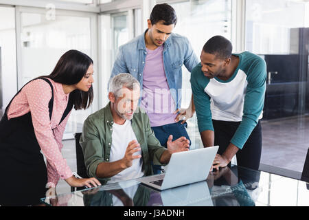 I colleghi guardando imprenditore spiegando mentre si lavora alla scrivania in ufficio Foto Stock