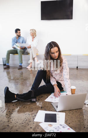 Per tutta la lunghezza della giovane imprenditrice utilizzando laptop sul piano presso il creative office Foto Stock