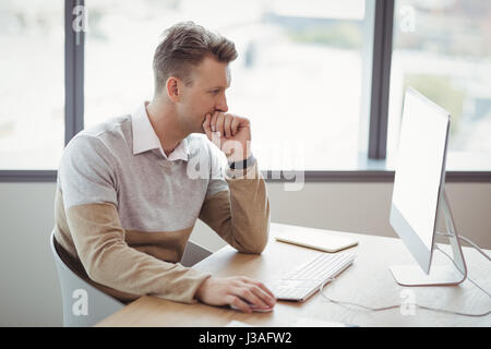 Attento lavoro esecutivo su personal computer presso la scrivania in ufficio Foto Stock