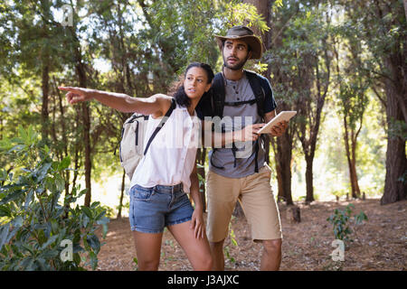Donna con puntamento uomo con Tablet PC in foresta Foto Stock
