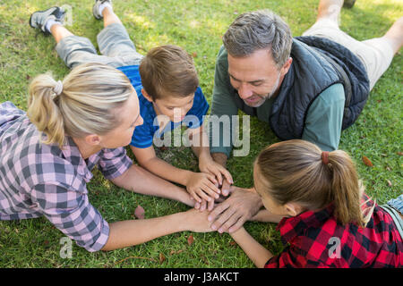 Famiglia giocoso giacenti e mettere le mani insieme in posizione di parcheggio Foto Stock