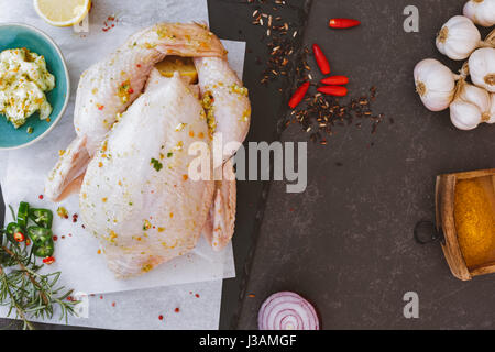 Tutto il pollo crudo sulla carta da forno con il condimento prima della cottura vista superiore vintage tonica immagine spazio di copia Foto Stock