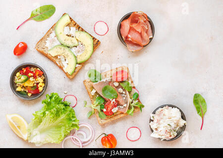 Aprire panini integrali e vari ingredienti sulla superficie rustico. Vista dall'alto, uno spazio vuoto Foto Stock