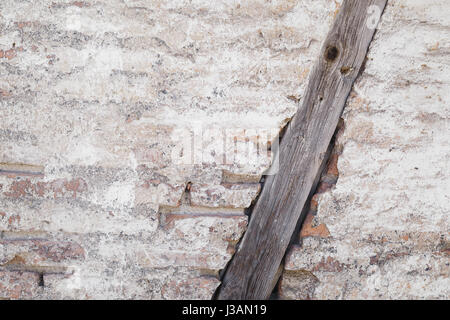 La texture di un muro di mattoni, incrinato intonaco e trave di legno, sfondo rustico Foto Stock