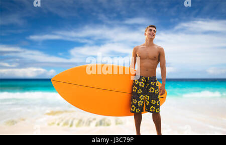 Sorridente giovane con la tavola da surf in spiaggia Foto Stock