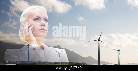 Imprenditrice con lo smartphone su turbine eoliche Foto Stock