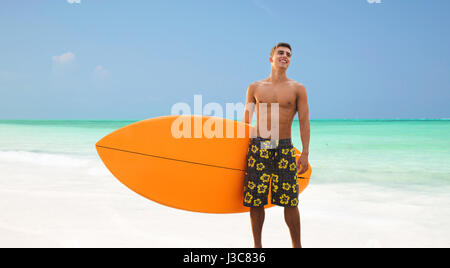 Sorridente giovane con la tavola da surf in spiaggia Foto Stock