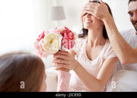 Felice ragazza dando ai fiori di madre nel letto di casa Foto Stock