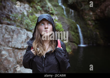 Giovane donna in piedi vicino a cascata in campagna Foto Stock
