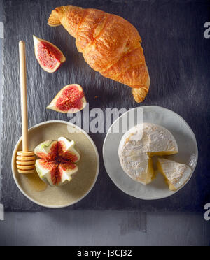 Croissant con formaggio morbido e figure su una lastra di pietra Foto Stock