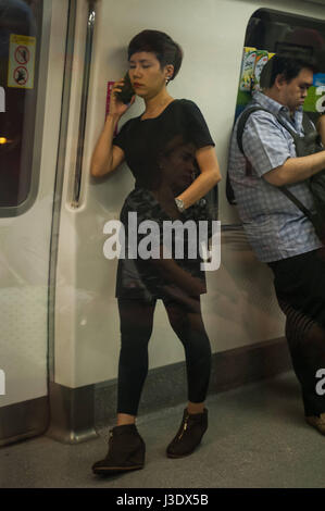 Singapore Repubblica di Singapore, Asia, una donna parla al telefono sulla stazione MRT Foto Stock