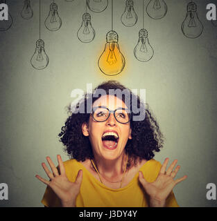 Ritratto super felice Excited donna in bicchieri cercando fino alla luce brillante idea lampadina sopra la testa isolata sul muro grigio sfondo Foto Stock