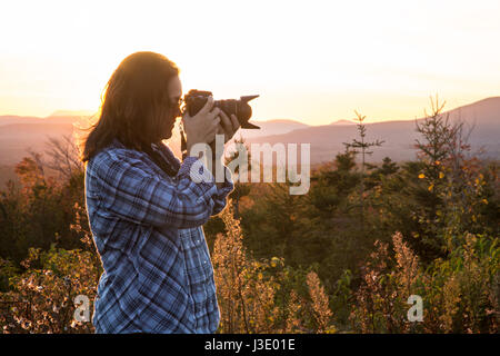 La donna a fotografare il tramonto nelle montagne del Maine Foto Stock