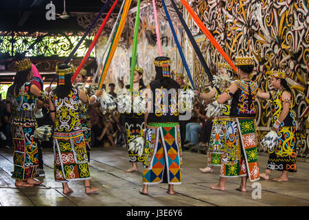 Ragazze Dayak esecuzione di danza culturale nel colorato costume tradizionale in una Longhouse Dayak a Pampang in East Kalimantan, Borneo Indonesiano. Foto Stock